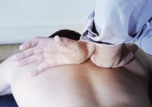 male physiotherapist massaging and easing tension in patient's back